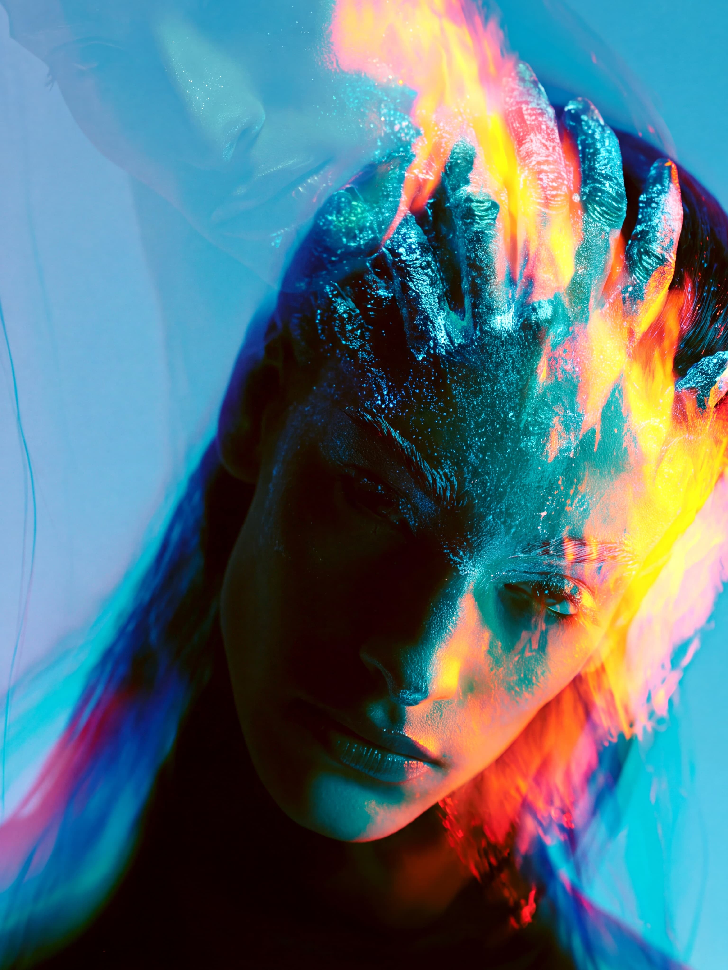 Close-up portrait with blue and orange light across a face against a vivid cyan background